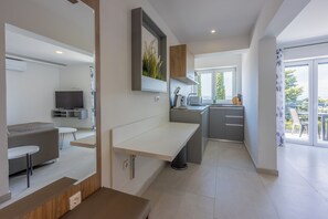 A modern kitchen with a built-in oven, a dining area with a bench, and a large window offering a view of the outdoors. - Modern vacation apartment with fantastic views and swimming pool (Crikvenica)