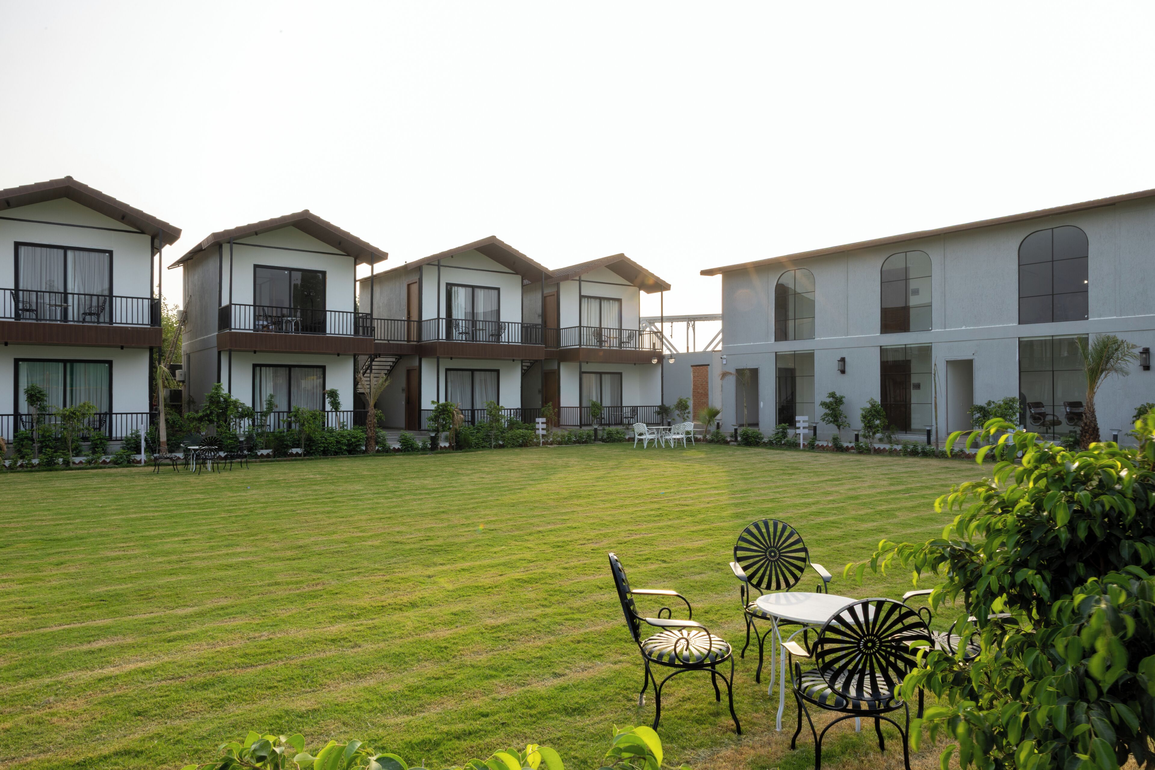 A courtyard with a lawn, outdoor seating, and a building with multiple balconies.