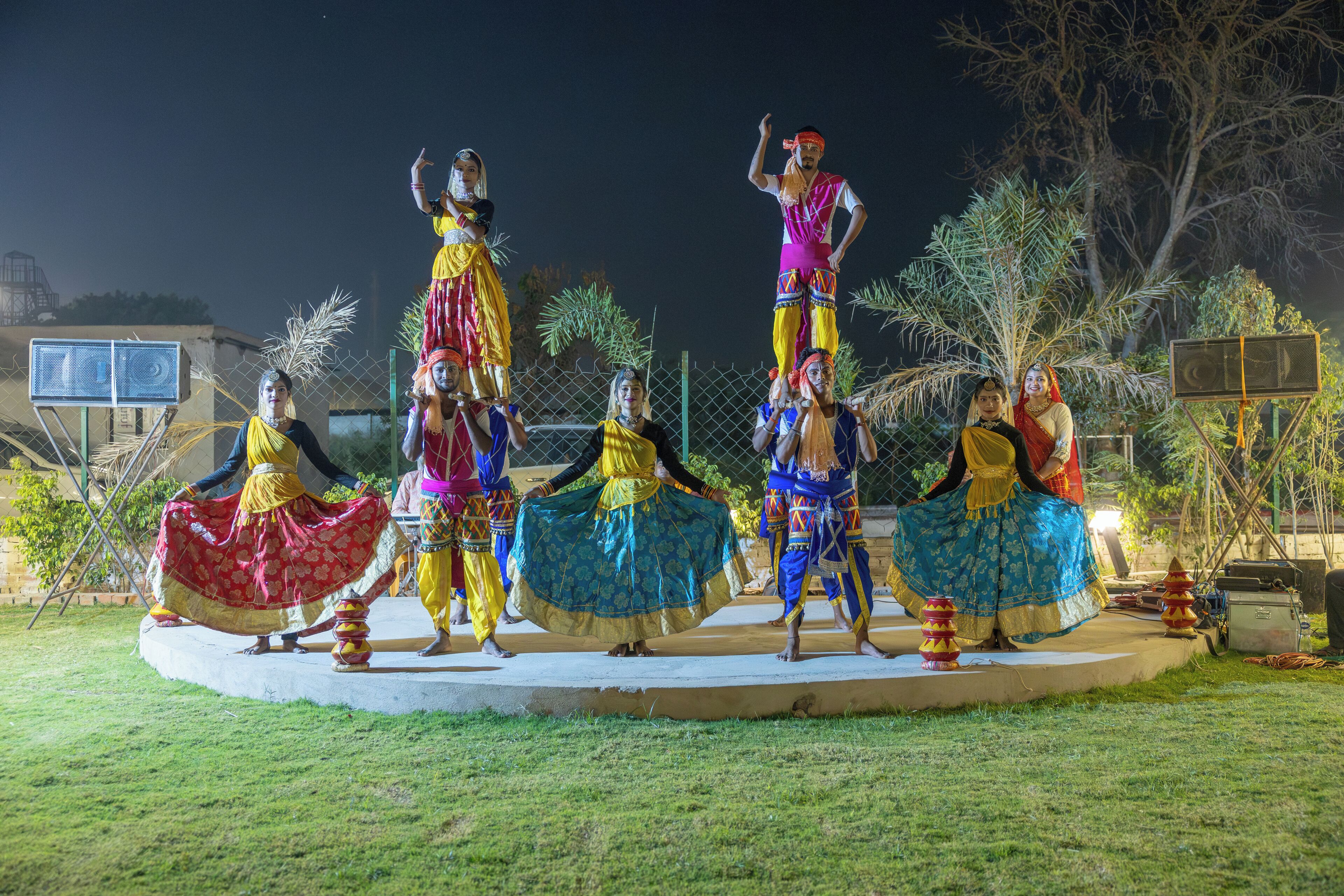 Un grupo de personas bailando sobre una plataforma circular al aire libre de noche.