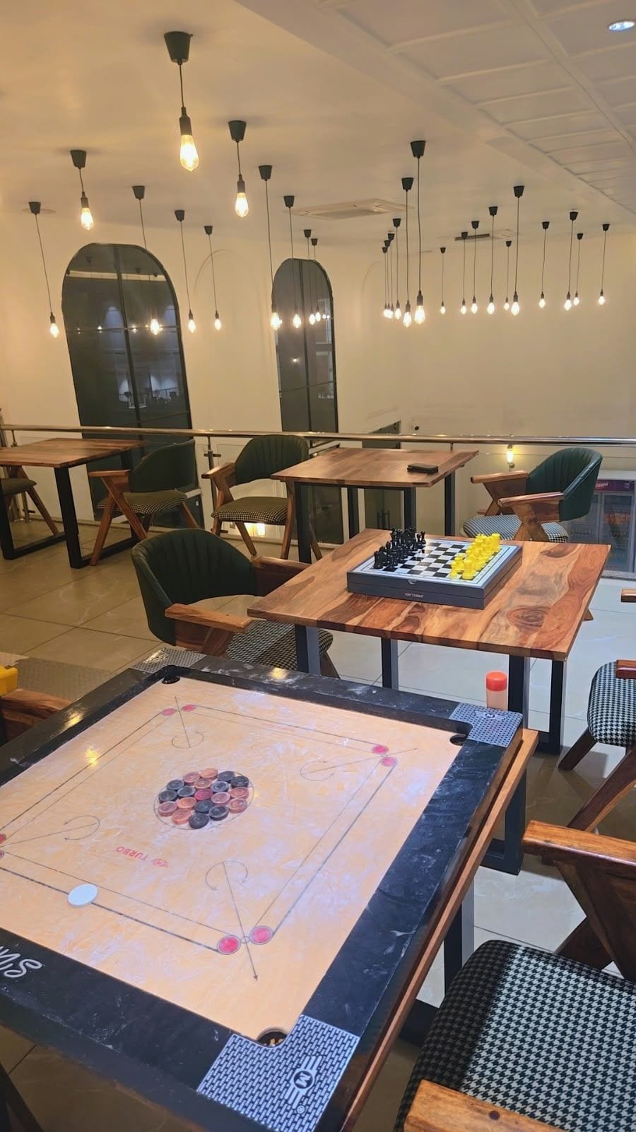 Una habitación con mesas, sillas, un juego de mesa e iluminación colgante.