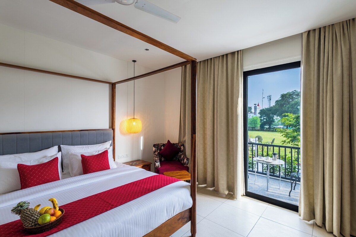 A hotel room with a bed, a fruit bowl, a chair, and a balcony with a view.