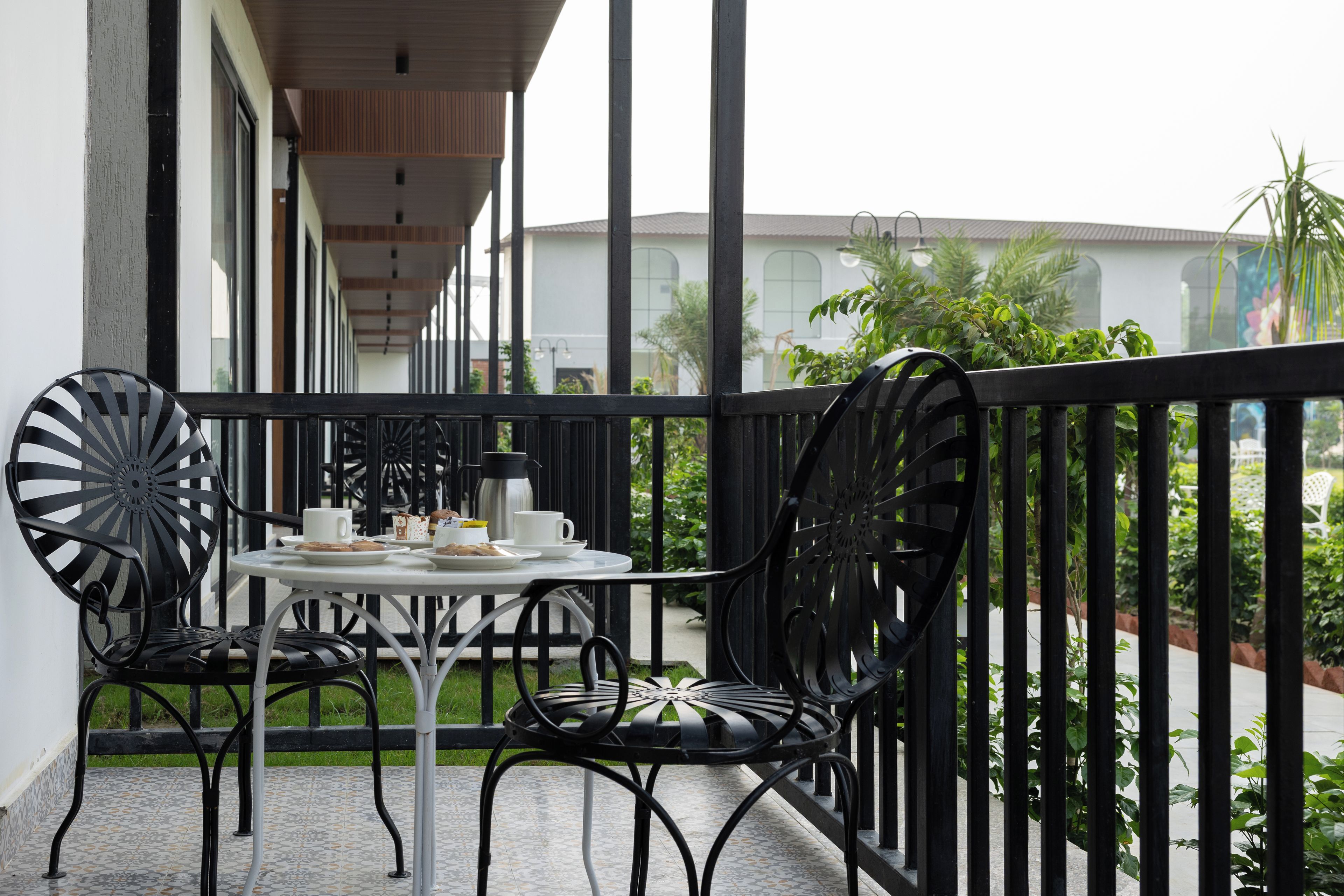 A balcony with a table and chairs, a coffee pot, and a cup.
