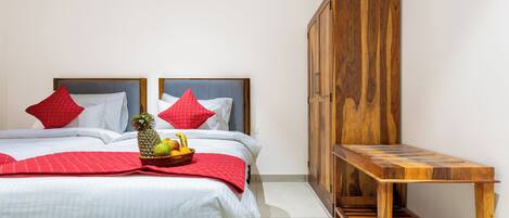 A hotel room with a bed, a wooden bench, and an air conditioning unit.