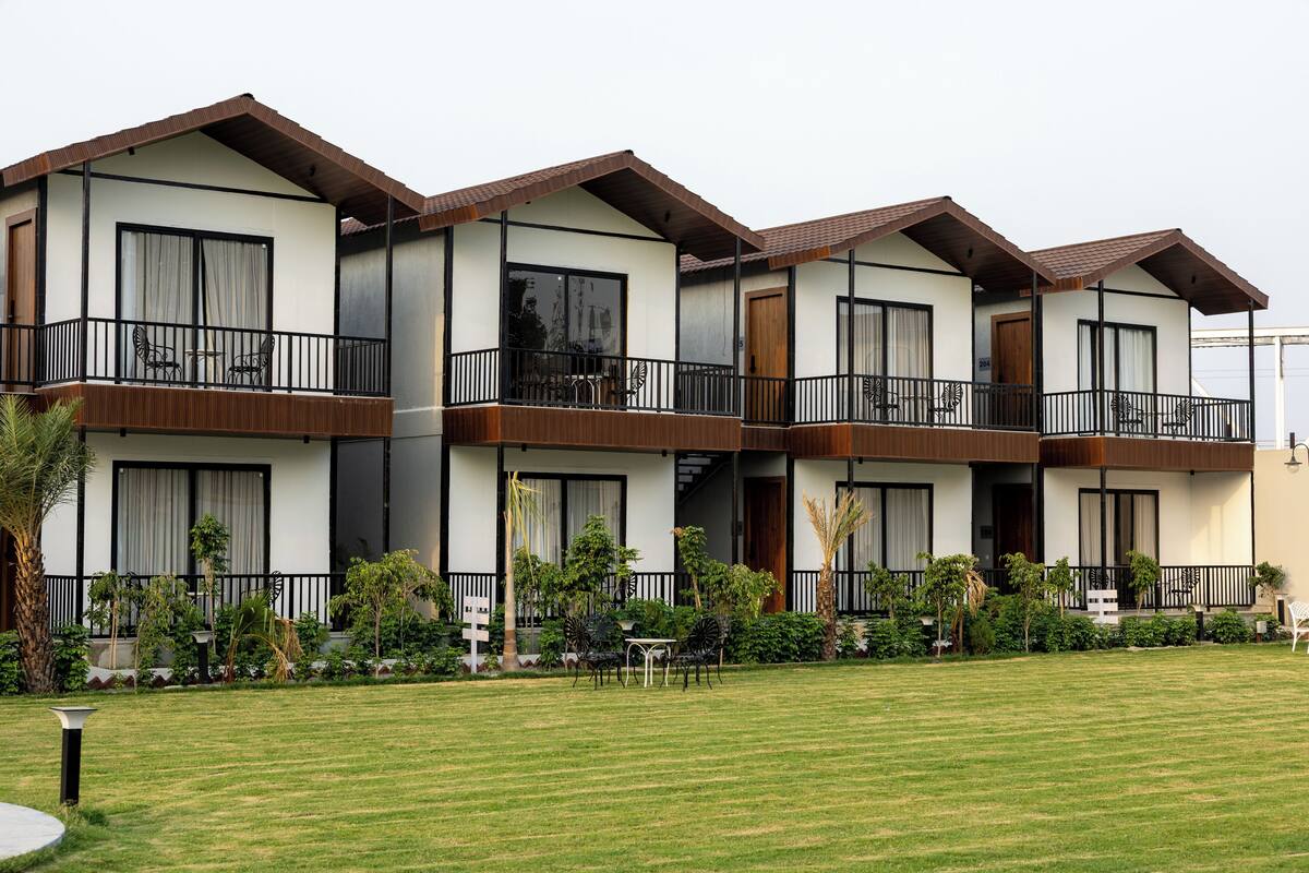 A multi-story hotel with balconies, outdoor seating, and a well-maintained lawn.