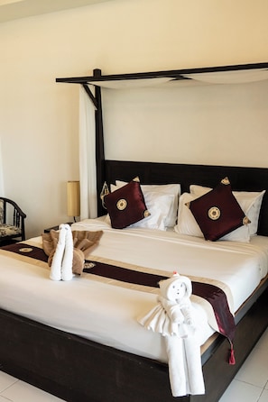 Een hotelkamer met een bed, kussens, een nachtkastje, een lamp en een stoel.