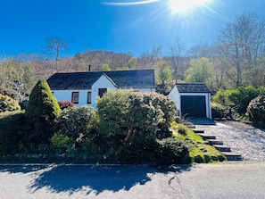 Ein zweigeschossiges Haus mit Garage, umgeben von gepflegten Büschen und Bäumen.