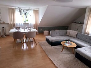 Un soggiorno moderno con zona pranzo, un divano grigio e un tavolino da caffè.