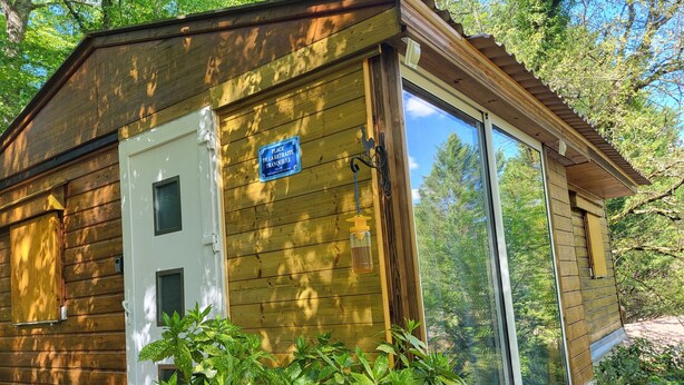 A small wooden cabin with a sign indicating a retreat place, a door, and a window. - CHALET RENTAL IN PERIGORD NOIR (Prats-du-Périgord)