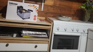 A kitchen with a white stove, a microwave, and a deep fryer on a wooden wall. - CHALET RENTAL IN PERIGORD NOIR (Prats-du-Périgord)