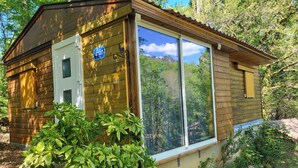 A wooden cabin with a large window, a door, and a sign indicating it is a guesthouse. - CHALET RENTAL IN PERIGORD NOIR (Prats-du-Périgord)