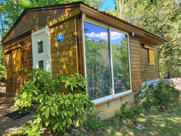 A wooden cabin with a large window, a door, and a sign indicating it is a guesthouse.