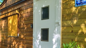 A wooden cabin with a white door, a small window, and a sign indicating a tranquil retreat. - CHALET RENTAL IN PERIGORD NOIR (Prats-du-Périgord)