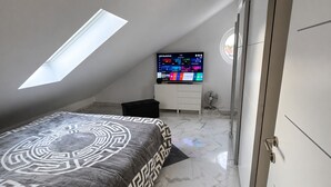 Une chambre à coucher avec un lit, une télévision, un ventilateur et une lucarne.