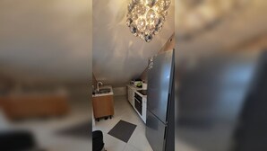 Une cuisine moderne dotée d’un réfrigérateur en acier inoxydable, d’un évier et d’un lustre original.