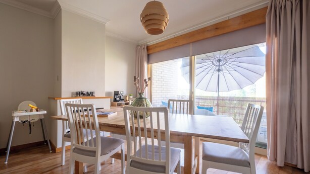 A dining area with a table, chairs, a hanging light fixture, a window with curtains, and a view of the outside. - FamilyHub - EcoHost | T2+1 - 8 people - A/C - Porto (Senhora da Hora)