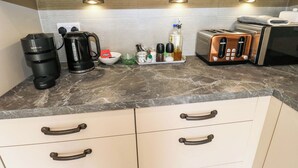 Ett kök med en kaffebryggare, en brödrost och diverse köksredskap på bänkskivan.