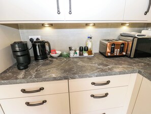 Eine Küche mit Kaffeemaschine, Toaster und verschiedenen Küchenutensilien auf der Arbeitsfläche.