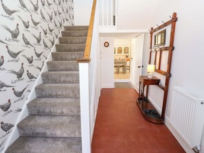 Eine Treppe mit Hahnen-Tapete, einer Holzhandläufe, einem Heizkörper und einem Flur, der zu einem Essbereich führt.