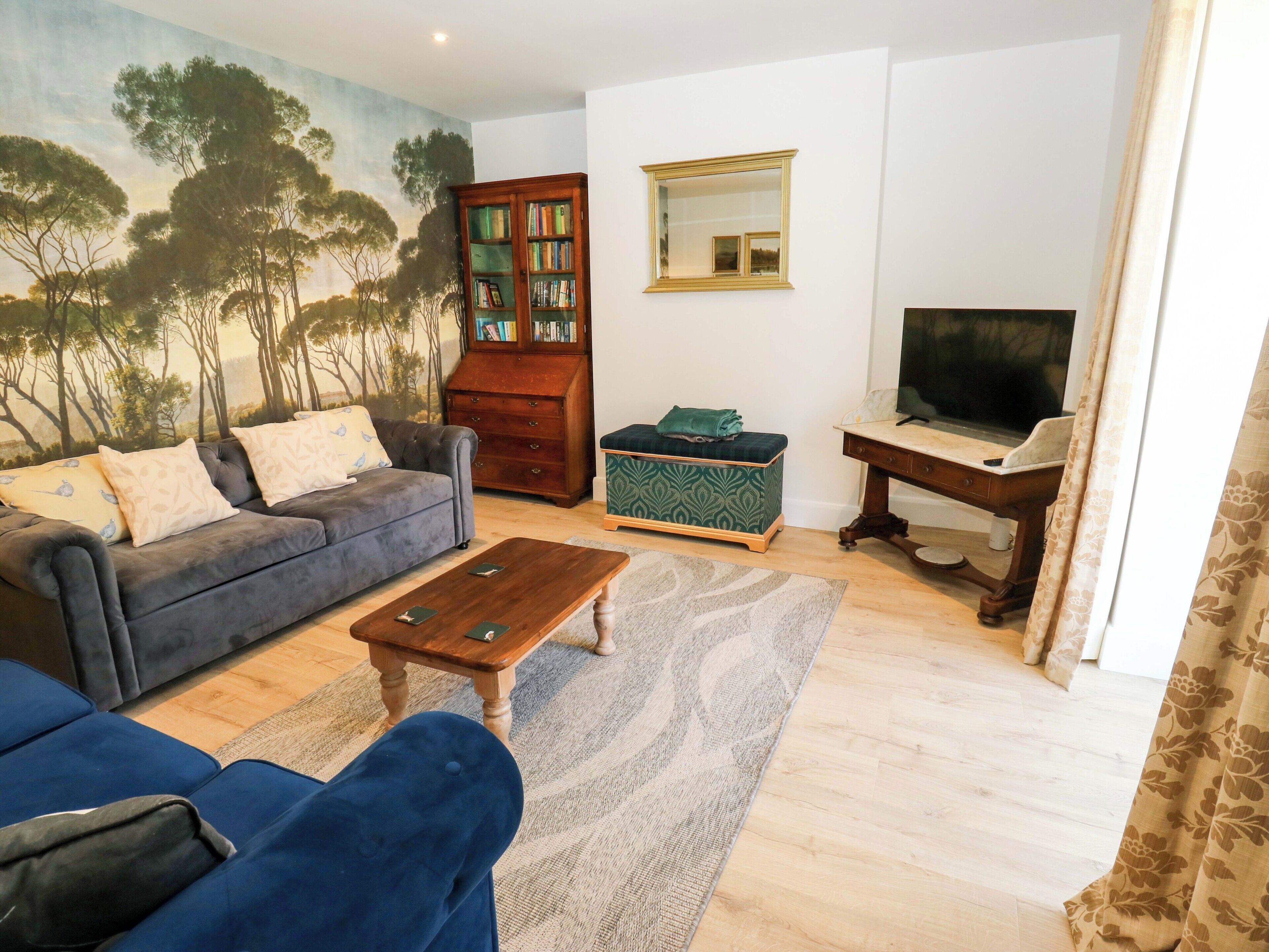 Een woonkamer met een bank, salontafel, tv-meubel en een boekenkast.
