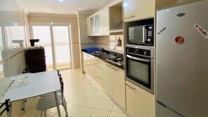 Une cuisine moderne équipée d’un réfrigérateur, d’un four, d’un four à micro-ondes et d’un coin repas avec une table et des chaises.