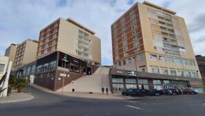 Un hôtel à plusieurs étages au design moderne, doté d’une entrée imposante et d’un espace de stationnement.