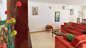 Un salon avec un canapé rouge, une petite table et une plante décorative.