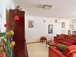 Un salon avec un canapé rouge, une petite table et une plante décorative.