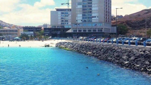 Un hôtel situé sur la côte, avec vue sur la plage, un parking et un rivage rocheux.
