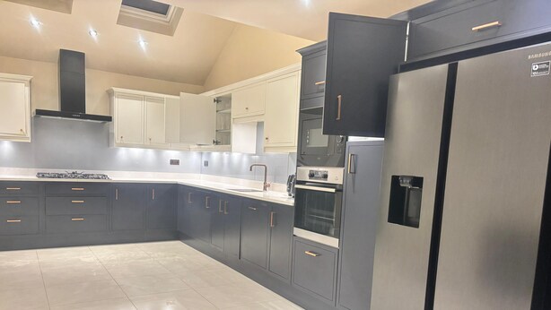 A modern kitchen with grey cabinets, stainless steel appliances, and a tiled floor.