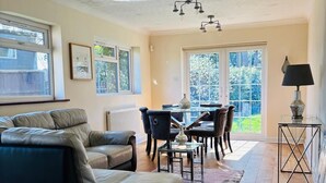 A spacious living room with a sofa, a dining table with chairs, and a lamp.
