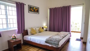 A bedroom with a wooden bed, purple curtains, a nightstand with a lamp, and a window with a view. - Winterbourne Chalet 3-bedroom villa in pleasant Coonoor getaway (Coonoor)