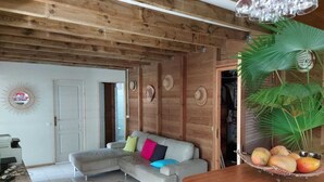 Un interior de madera con un sofá, una mesa de comedor con fruta y un ventilador.