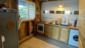 Una cocina rústica con vigas de madera, refrigerador, horno, pileta y lavadora.