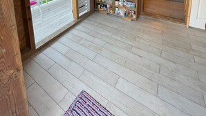 Interior de madera con área de cocina, estante con utensilios y vista al exterior.