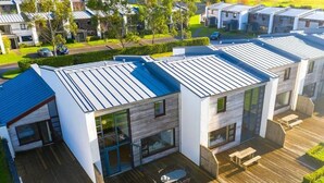 A modern residential building with a flat roof, large windows, and a wooden deck with outdoor furniture. - Luxury 2 Bed Lodge, Beside Castlemartyr Resort (Castlemartyr)