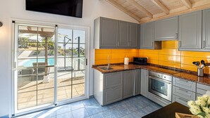 A modern kitchen with grey cabinets, a stainless steel oven, and a granite countertop. - Casa Yuliana: Private Heated Pool and Sea Views (Tijarafe)
