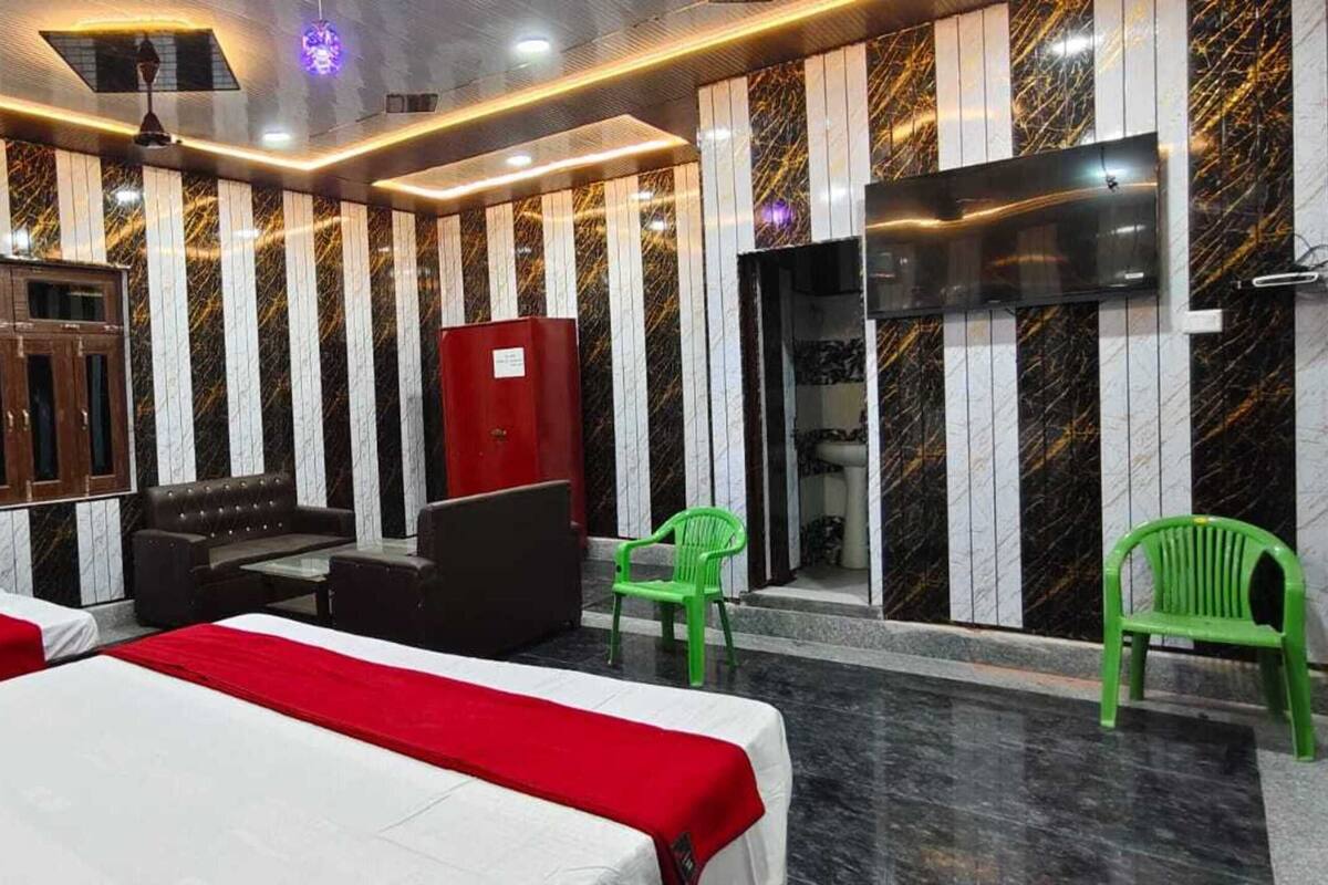 A hotel room with two beds, a TV, a red cabinet, and a green chair.
