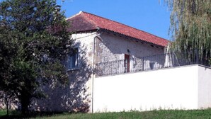A building with a red-tiled roof, a white exterior, and a metal fence. - GITE HIBISCUS (Sanilhac)