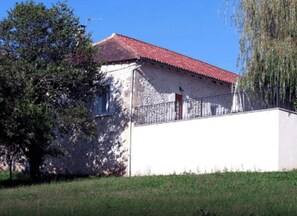 Ein Gebäude mit rotem Ziegeldach, weißer Fassade und einem Metallzaun.