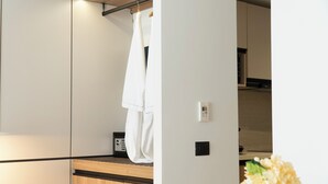 Ein modernes Badezimmer mit einem Holzkosmetikschrank, einem Handtuch auf einem Haken, einem Radio und einem Thermostat an der Wand.