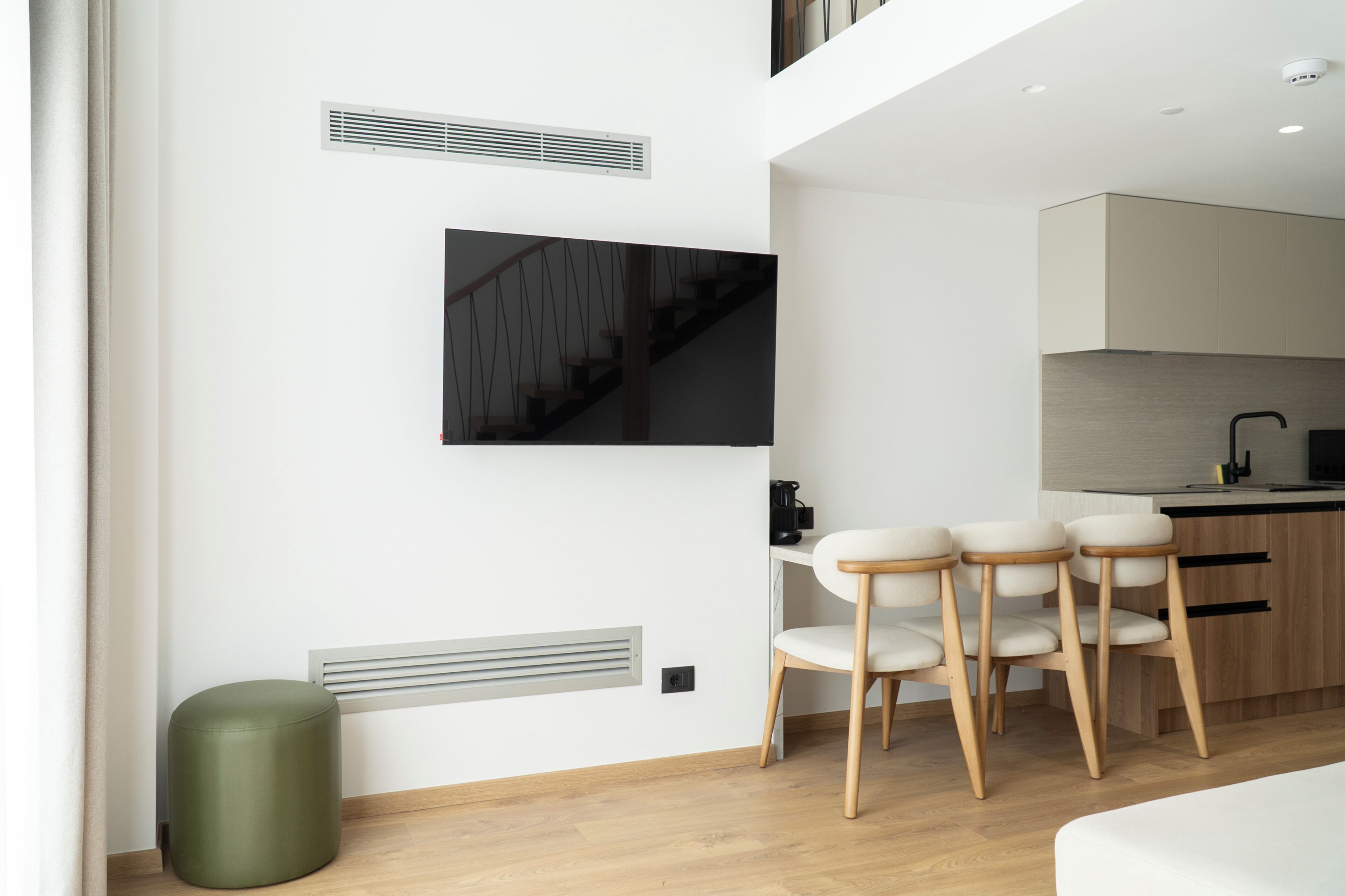 Una cocina moderna con comedor, un sofá y un televisor en la pared.