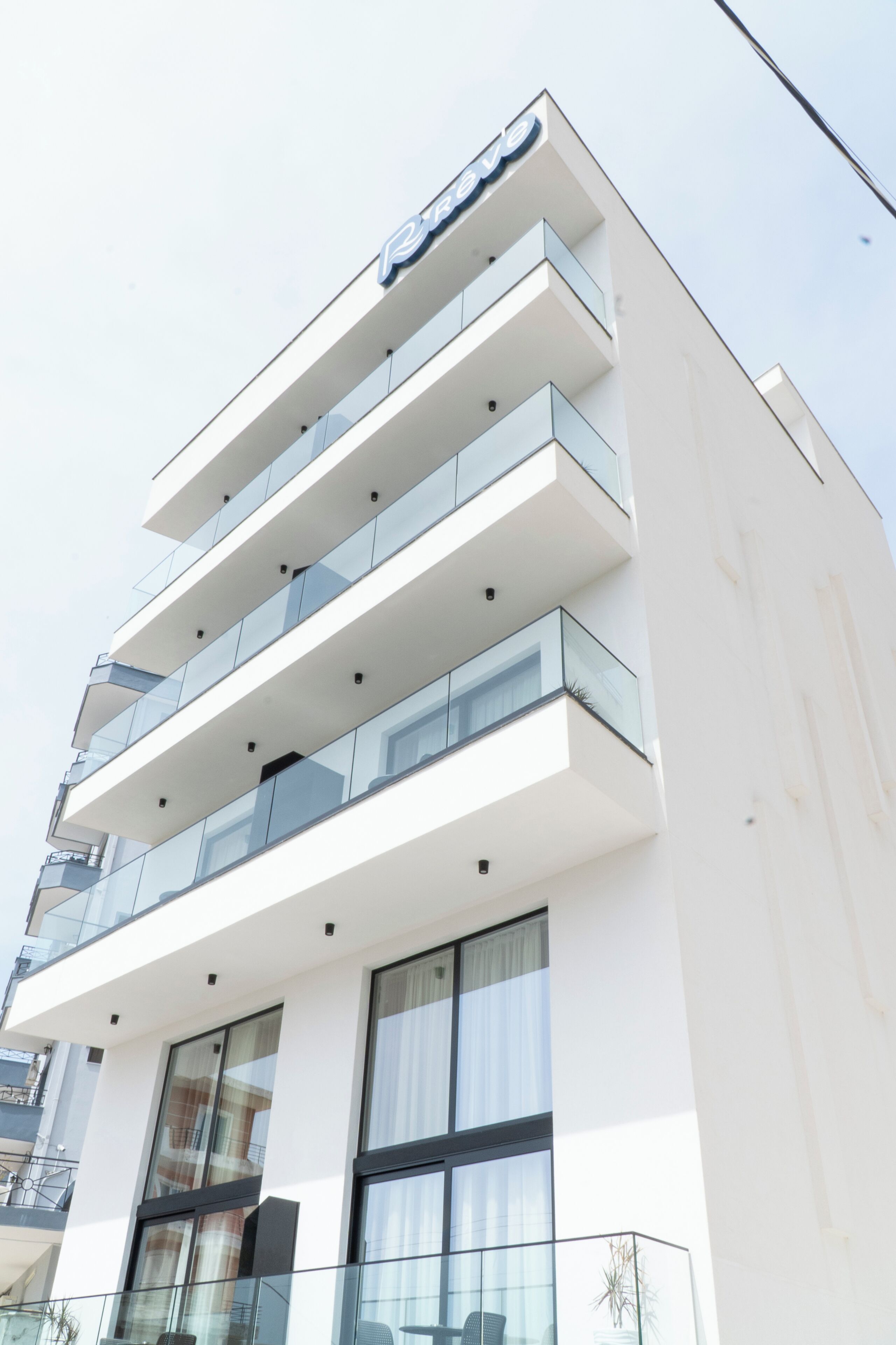 A modern building with multiple balconies, large windows, and a sign indicating it is a hotel.