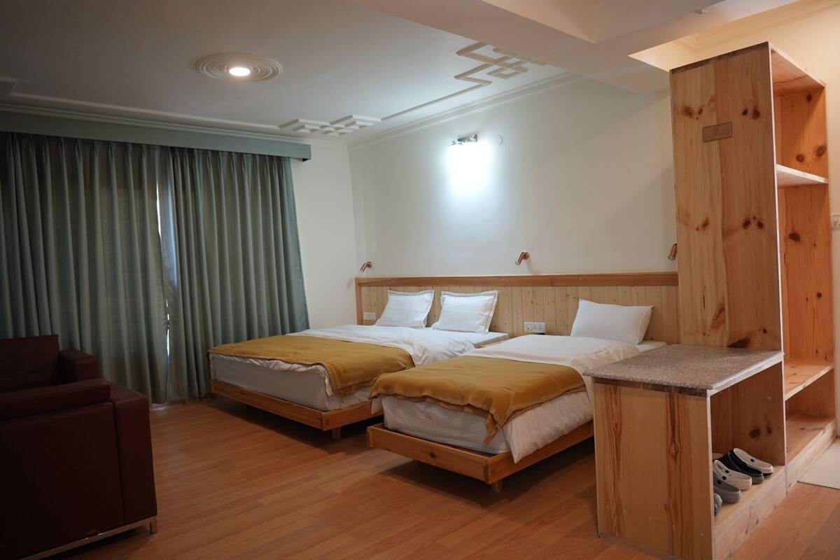 A hotel room with two beds, a wooden headboard, a desk, and a chair.