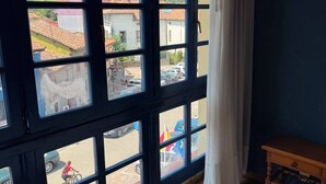 A room with large windows, a wooden floor, and a view of a town with buildings and hills. - HOTEL CUEVAS DEL MAR (Nueva)