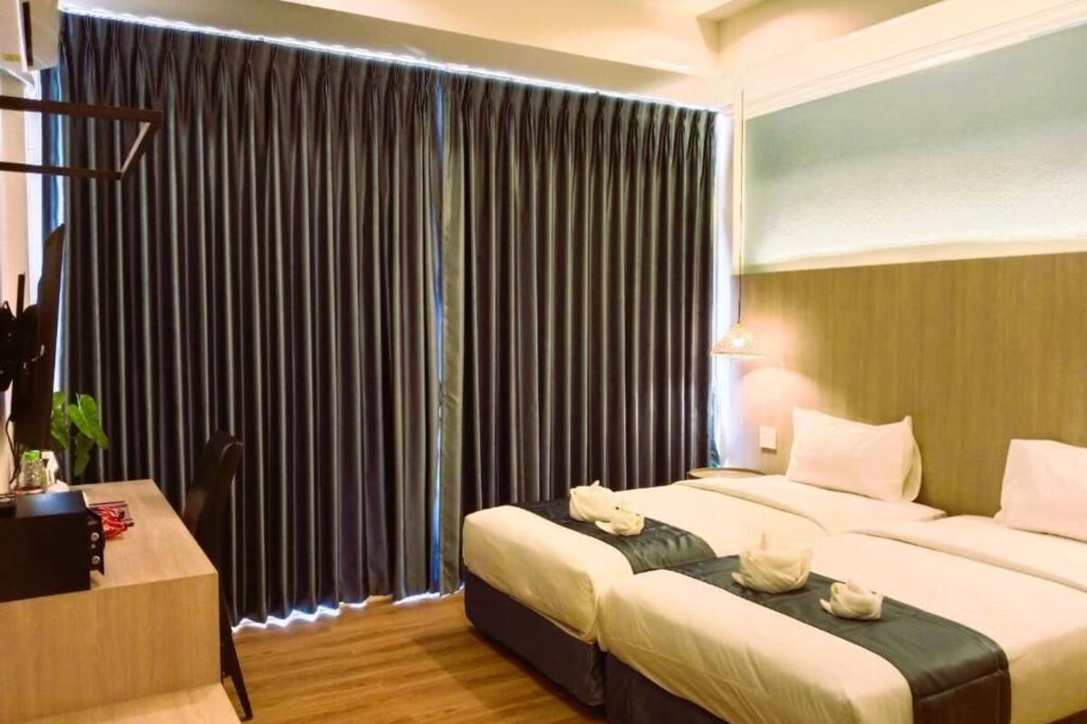 A hotel room with a bed, bedside tables, a desk, and a curtain.