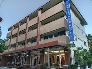 A multi-story hotel with a prominent sign, balconies, and a covered entrance area. - Eastique Hotel Koh Chang (Ko Chang)