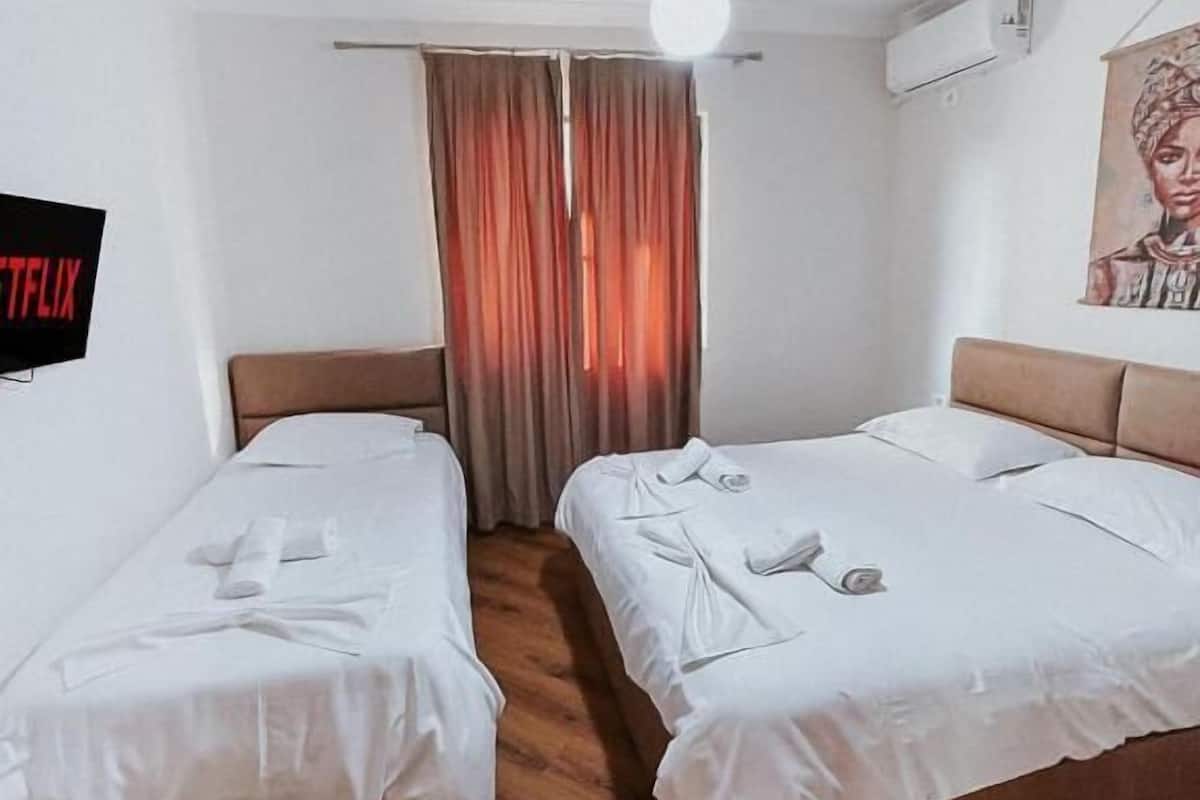 Ein Hotelzimmer mit zwei Betten, einem Fernseher und einem Bild an der Wand.