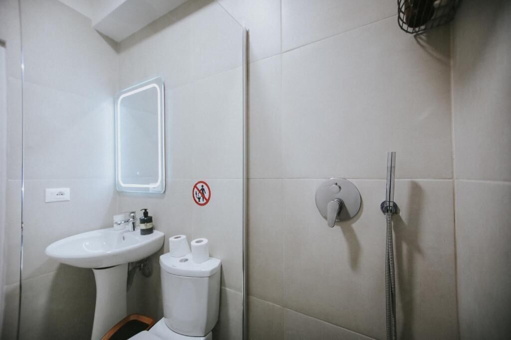 A bathroom with a sink, toilet, mirror, and shower.