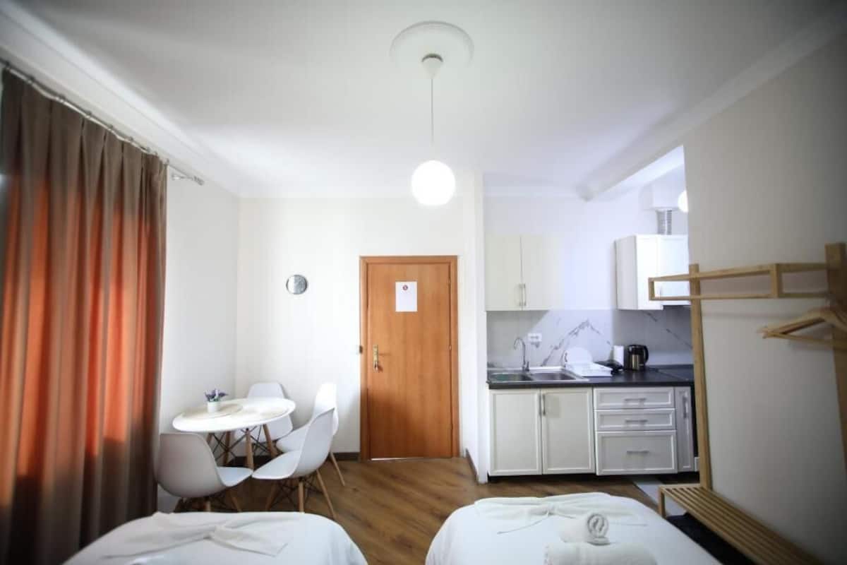 Ein kompaktes Hotelzimmer mit zwei Betten, einer kleinen Küchenzeile, einem Essbereich und einem Badezimmer.