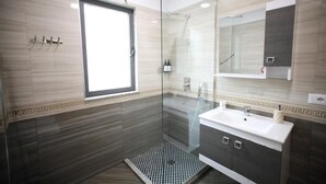 A modern bathroom with a glass-enclosed shower, a sink with a vanity, and a large mirror. - Villa Reve de Tirana (Tirana)